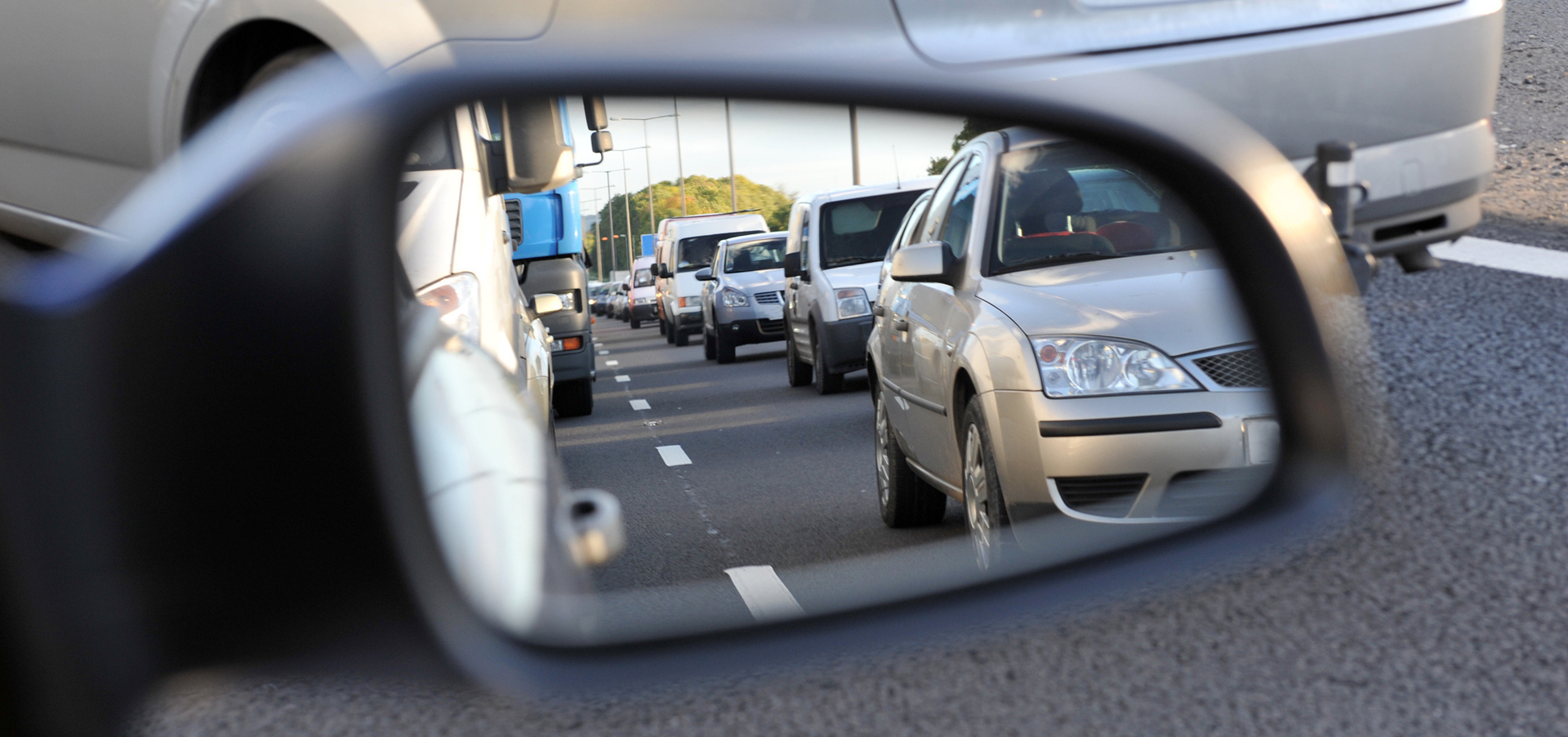 Looking through a car's wing mirror at a long queue of traffic