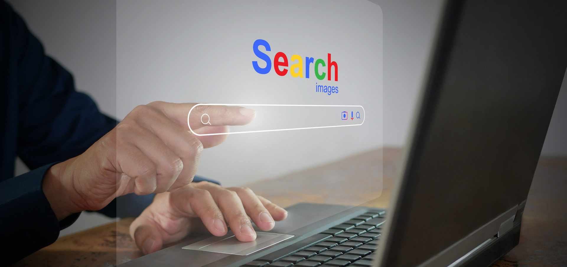 A person sat at a desk browsing the web, making a google search